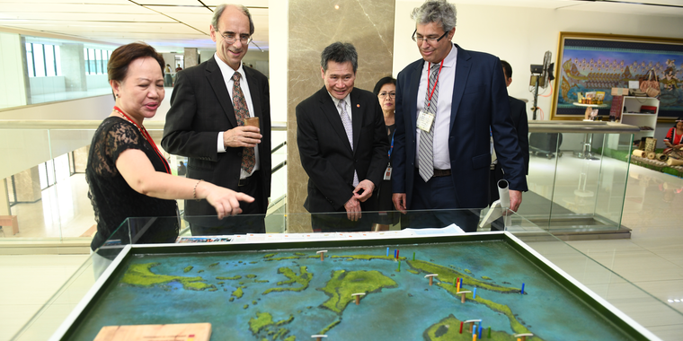 A woman shows three men a map of ASEAN.