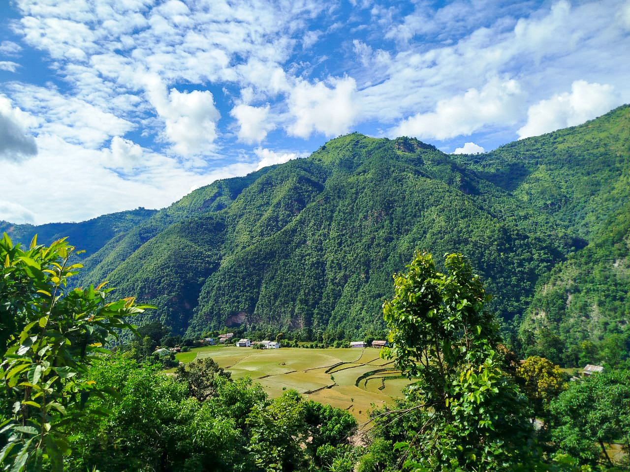 A farming valley and village in a forested area in Nepal.